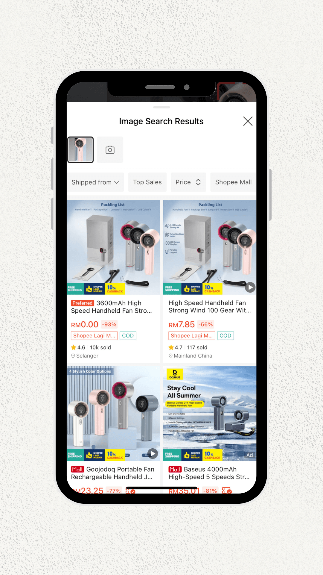 Image of a smartphone screen displaying search results for handheld fans. Various models with prices and discounts on an online shopping app are visible.